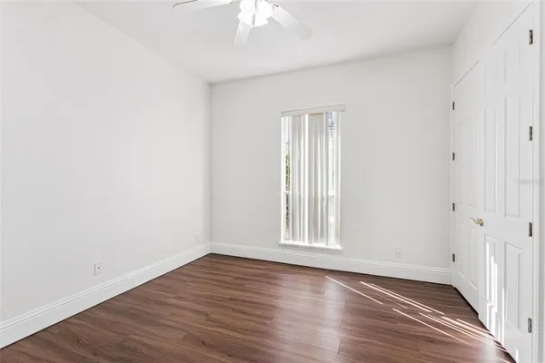 an empty room with wooden floor chandelier fan and windows