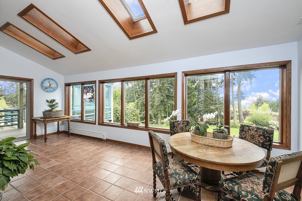 5741 Crow Haven Road Langley, WA 98260 - Photo 15 of 40 a view of a dining room with furniture large windows and wooden floor