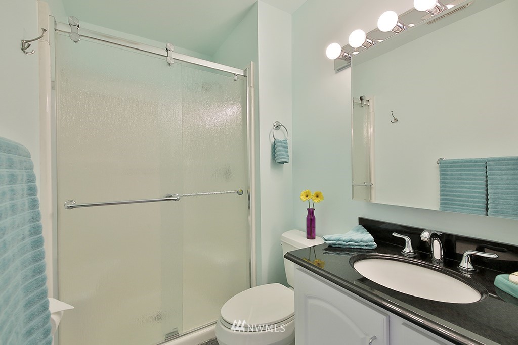 5741 Crow Haven Road Langley, WA 98260 - Photo 25 of 40 a bathroom with a granite countertop sink toilet a mirror a vanity and shower