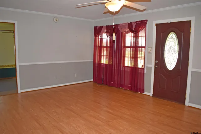 an empty room with a chandelier fan and windows