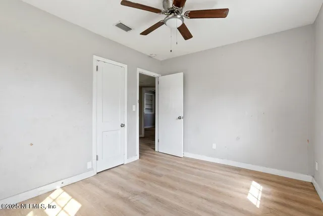 a view of a room with wooden floor and a ceiling fan