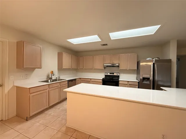 a kitchen with stainless steel appliances kitchen island granite countertop a sink a stove top oven and white cabinets