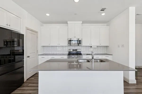 a kitchen with stainless steel appliances granite countertop a refrigerator a stove and a sink