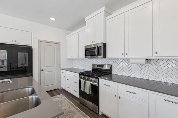a kitchen with granite countertop white cabinets and stainless steel appliances