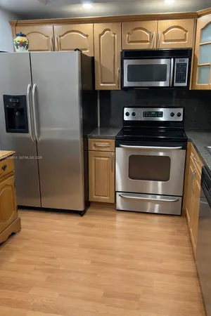 a kitchen with stainless steel appliances granite countertop a refrigerator and a stove