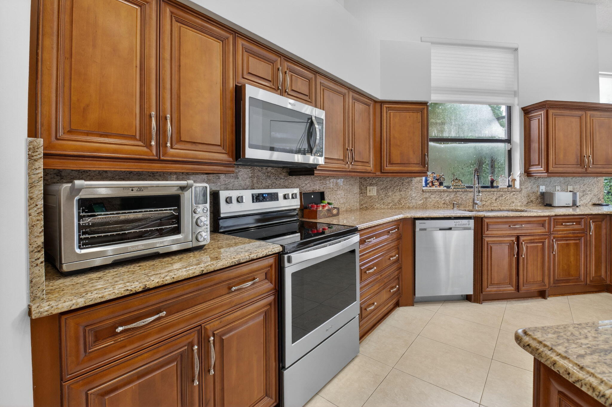 2462 Northwest 63rd Street Boca Raton, FL 33496 - Photo 9 of 41 a kitchen with stainless steel appliances granite countertop a stove microwave and cabinets