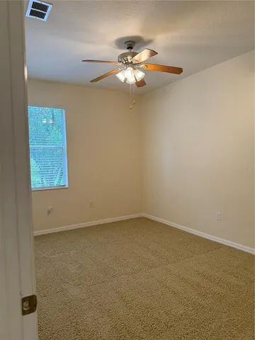 an empty room with a chandelier fan and windows