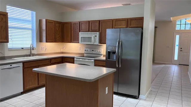 a kitchen with stainless steel appliances granite countertop a refrigerator a sink and a stove