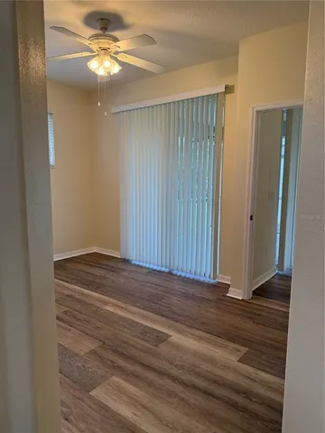 an empty room with wooden floor fan and windows