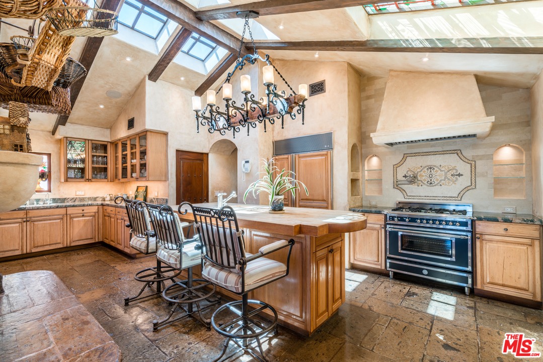 22102 Pacific Coast Highway Malibu, CA 90265 - Photo 15 of 36 a kitchen with stainless steel appliances a stove a sink dishwasher a dining table and chairs with wooden floor