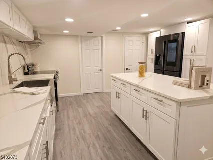 a large white kitchen with a stove a sink a refrigerator and a refrigerator