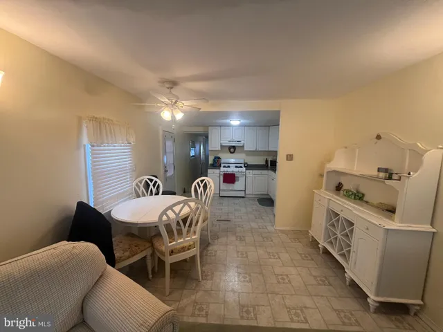 a kitchen with stainless steel appliances kitchen island granite countertop a sink a stove a refrigerator a microwave oven with white cabinets and couches