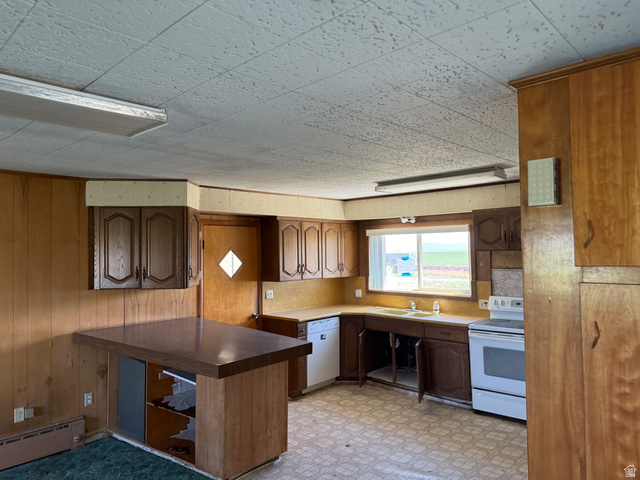 2002 Lund Road Bancroft, ID 83217 - Photo 7 of 28 Kitchen featuring wood paneling, wood cabinetry, a built-in breakfast bar, a window above the sink, and a white electric range