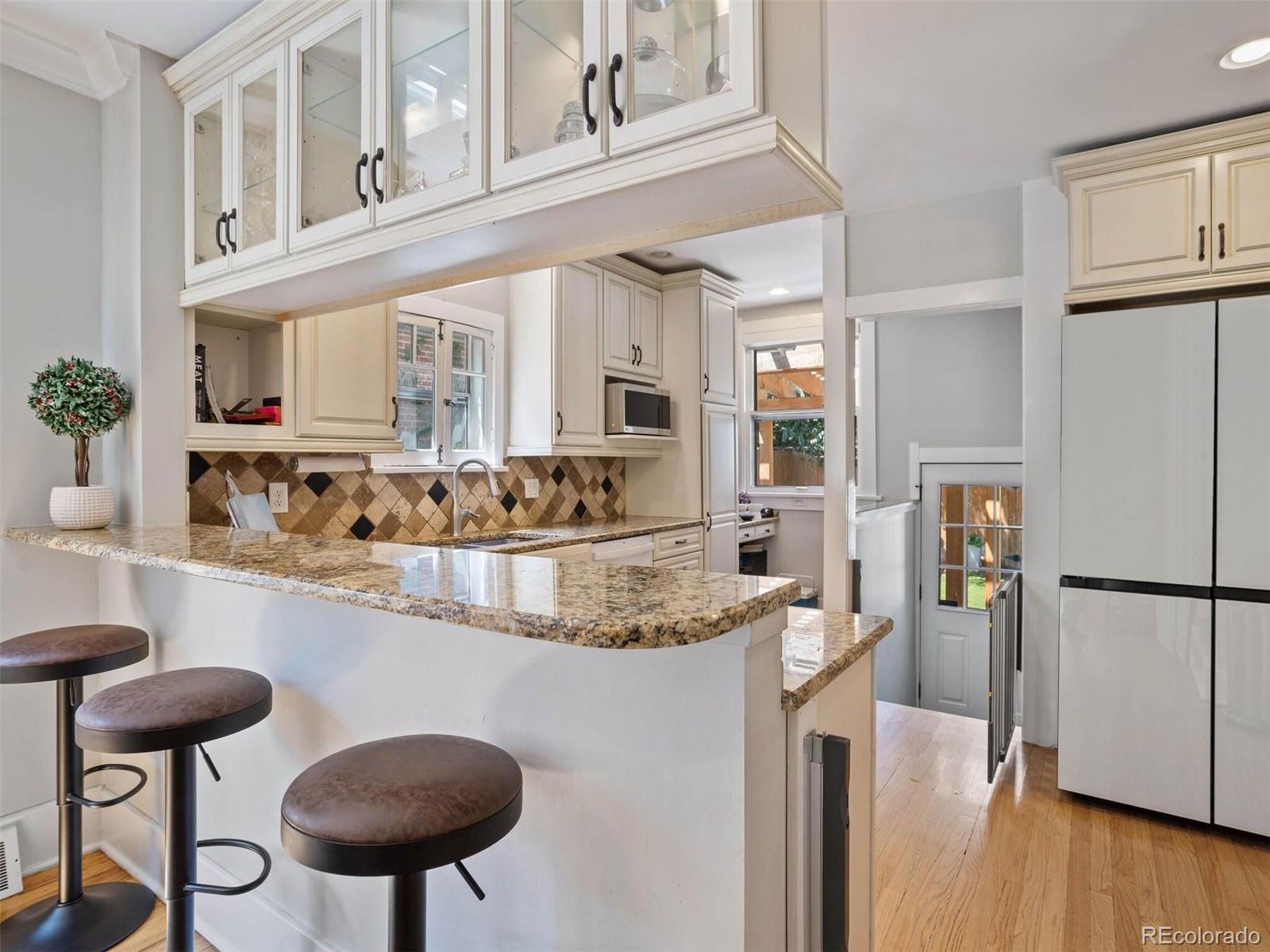643 Jackson Street Denver, CO 80206 - Photo 14 of 40 a kitchen with stainless steel appliances granite countertop a refrigerator a stove and white cabinets