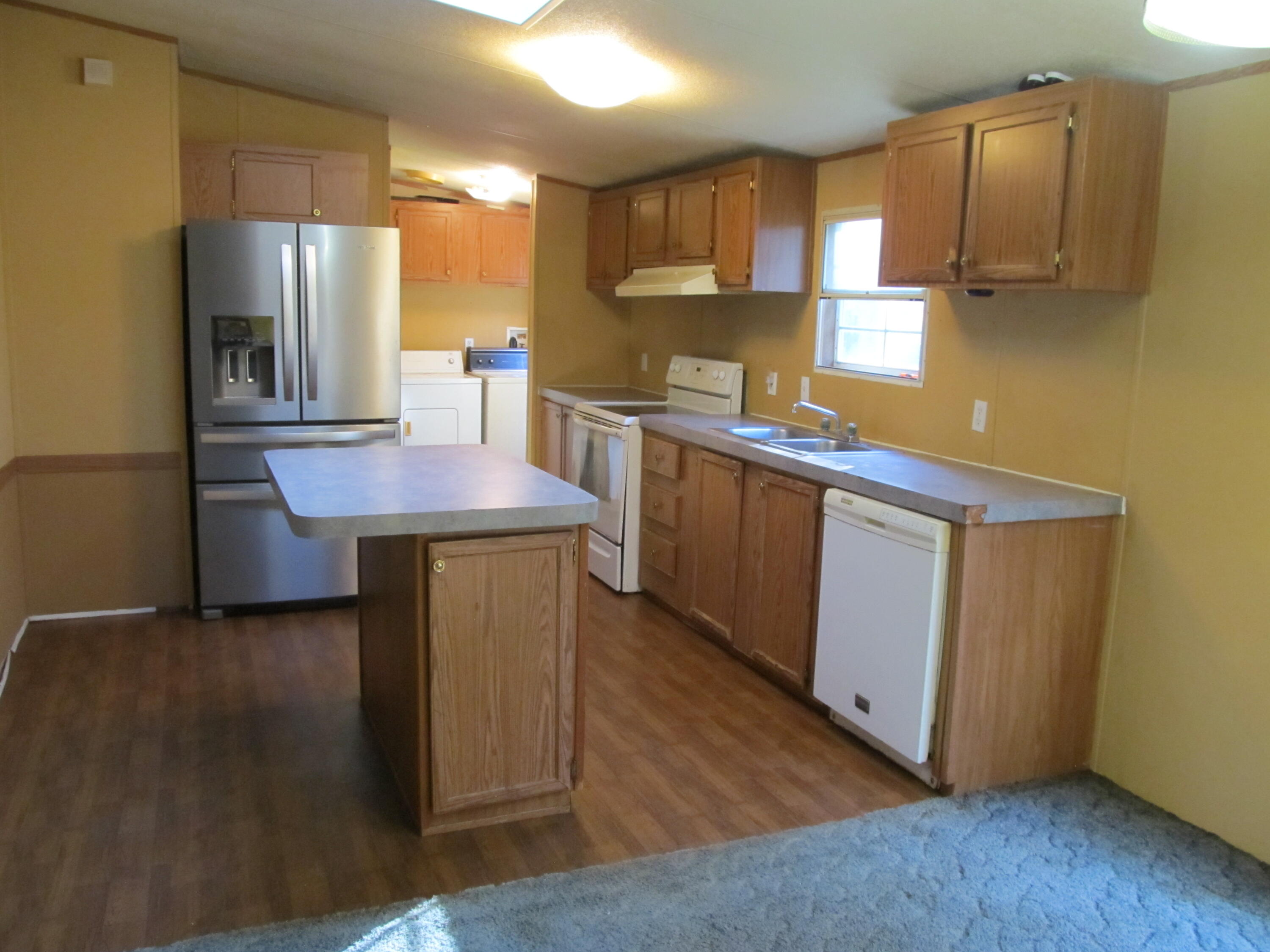 211 River Road Samson, AL 36477 - Photo 5 of 23 a kitchen with stainless steel appliances granite countertop a sink a stove a refrigerator a microwave oven with wooden floor