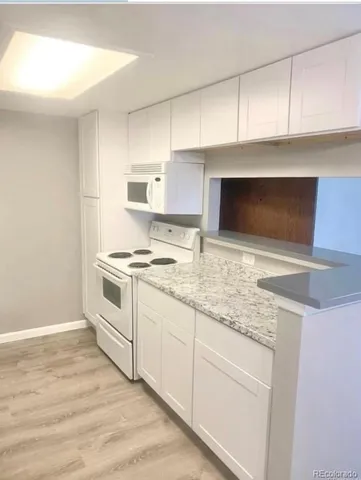 a kitchen with granite countertop white cabinets and white appliances