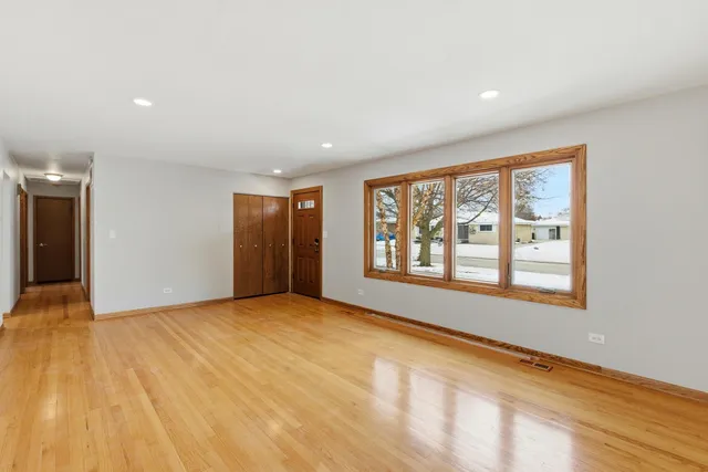 a view of an empty room with a window and wooden floor