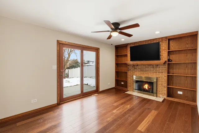 a living room with stainless steel appliances wooden floor and a fireplace