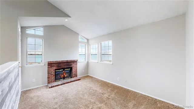 an empty room with windows and fireplace