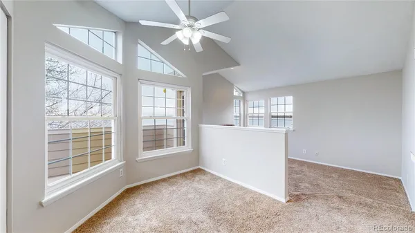 an empty room with chandelier fan and windows