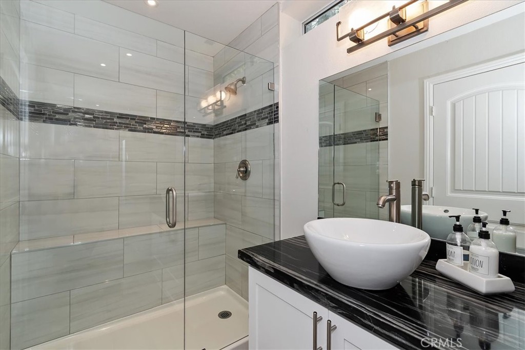 27565 North Bay Road Lake Arrowhead, CA 92352 - Photo 37 of 58 a bathroom with a granite countertop sink a mirror and shower