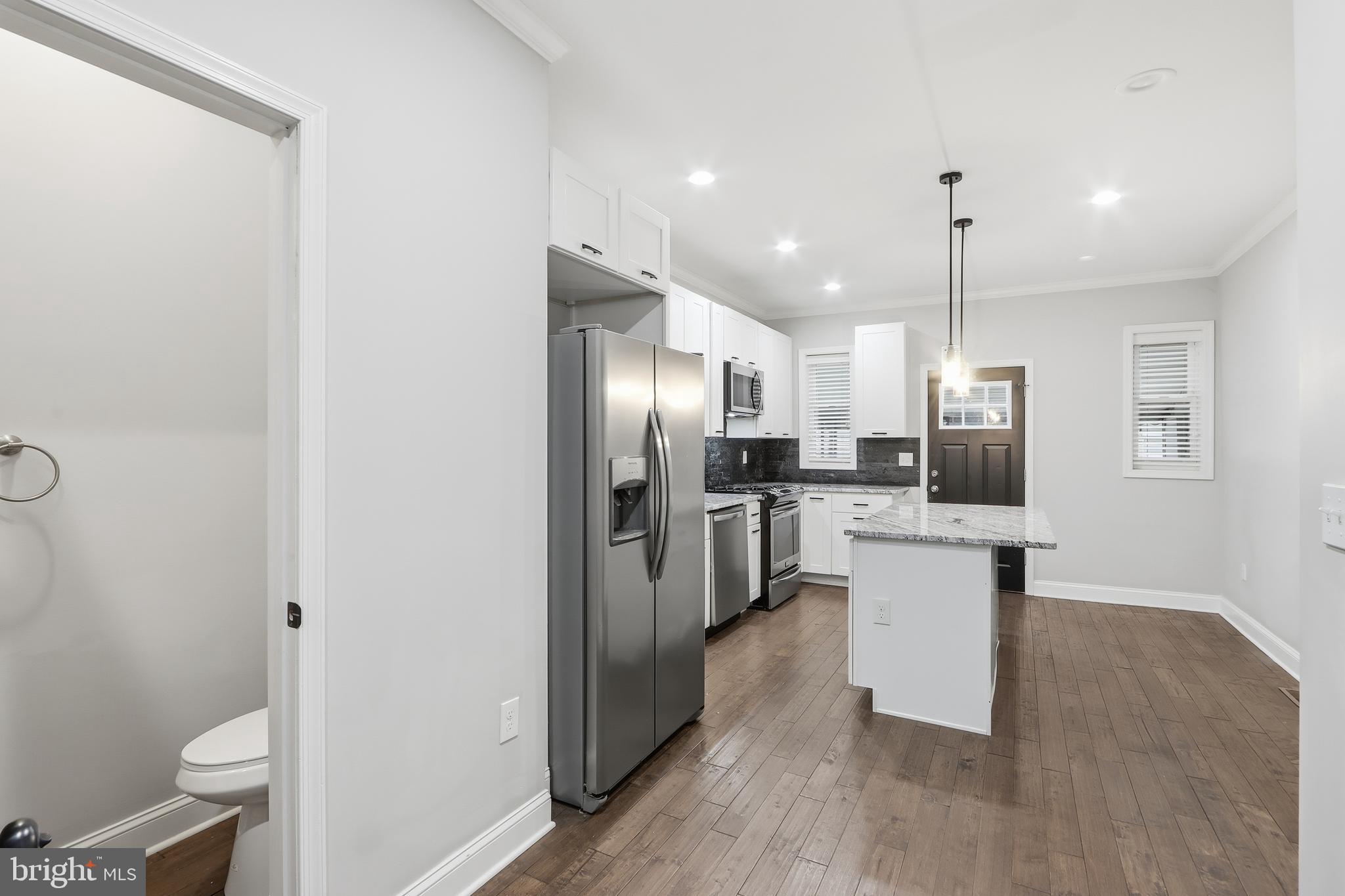 3540 Keswick Road Baltimore, MD 21211 - Photo 12 of 41 a kitchen with stainless steel appliances kitchen island granite countertop a refrigerator a sink a stove and white cabinets with wooden floor