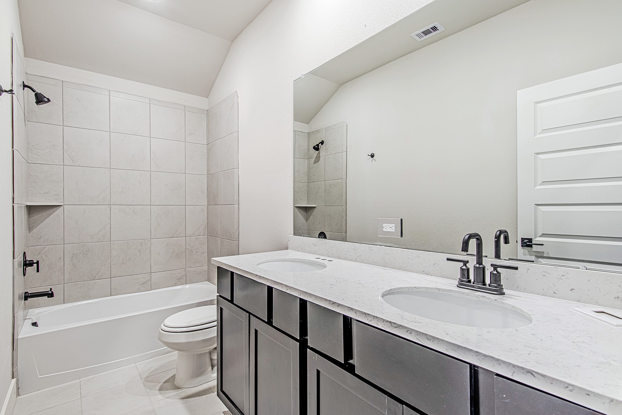 141 Peninsula Point Drive Montgomery, TX 77356 - Photo 37 of 47 Stylish full bathroom with dual sinks, sleek matte black fixtures, a large mirror, and a beautifully tiled shower/tub combo.