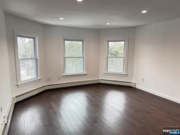 an empty room with wooden floor and window