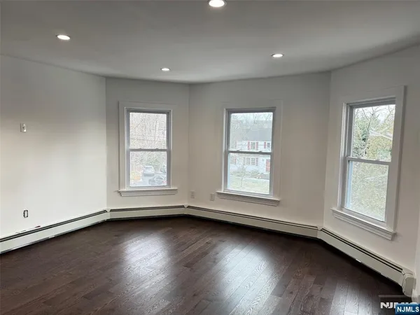 an empty room with wooden floor and windows with curtains view