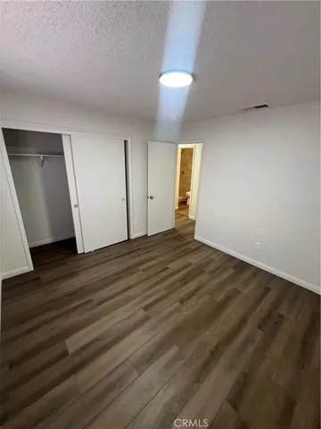 a view of an empty room with wooden floor and closet