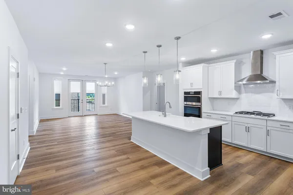a large kitchen with stainless steel appliances kitchen island granite countertop a large stove a sink dishwasher and white cabinets with wooden floor