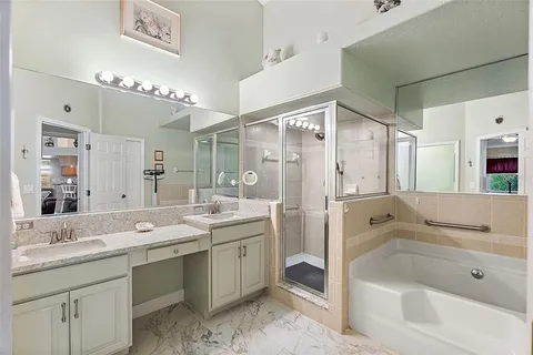 a bathroom with a tub a sink double vanity and a mirror
