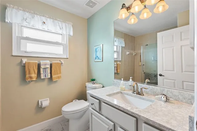 a bathroom with a granite countertop toilet sink and mirror