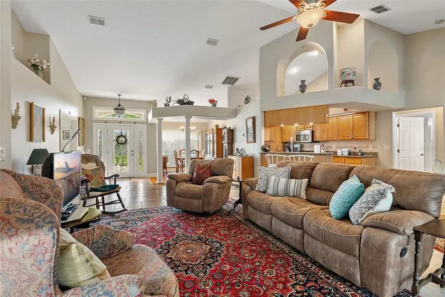 a living room with furniture kitchen view and a chandelier