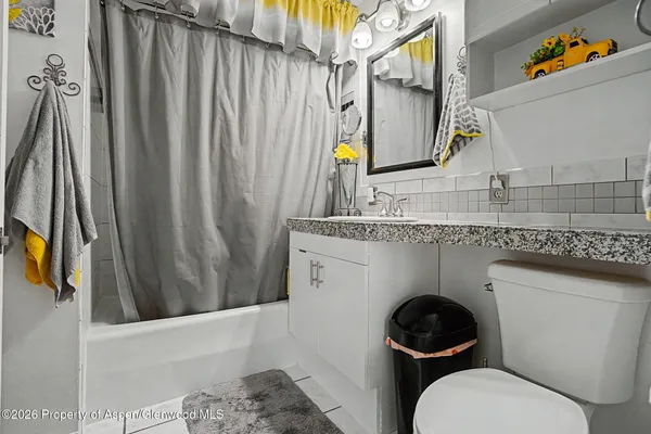 a bathroom with a granite countertop toilet sink and mirror