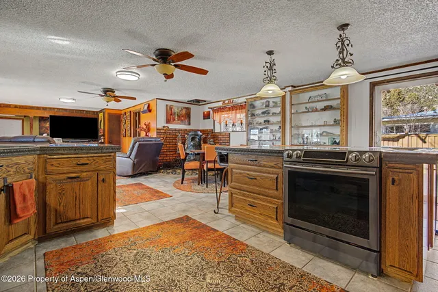 a kitchen with stainless steel appliances granite countertop a stove top oven a sink dishwasher and a fireplace with wooden floor