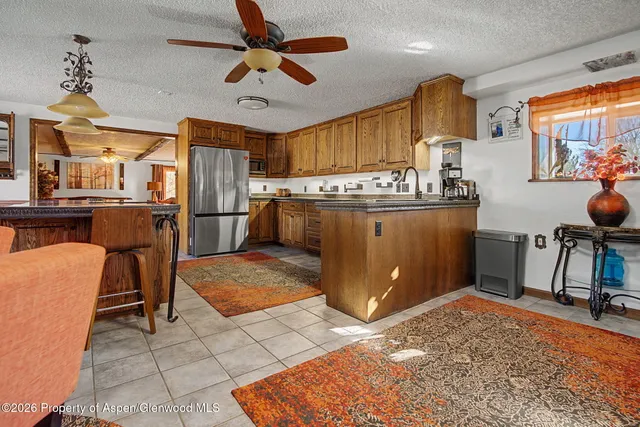 a room with stainless steel appliances kitchen island granite countertop furniture and a refrigerator