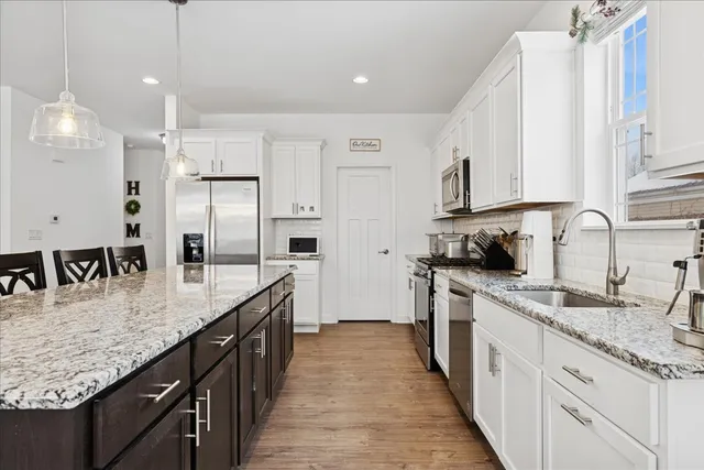 a kitchen with stainless steel appliances granite countertop a sink a stove and a refrigerator