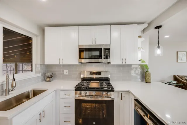 a kitchen with granite countertop a stove a sink and a microwave