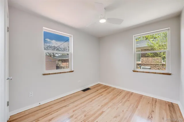 a view of empty room with wooden floor and fan