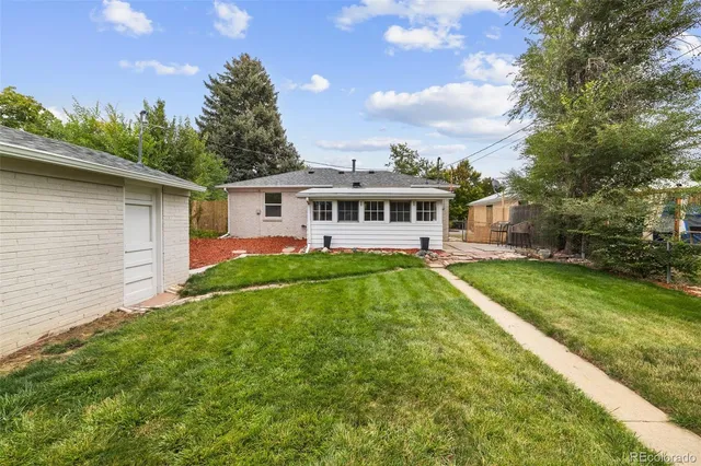 a view of a house with a big yard plants and large trees