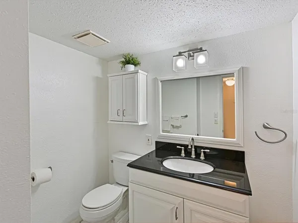 a bathroom with a granite countertop sink a toilet and a mirror
