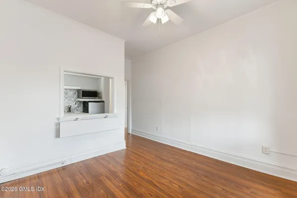 an empty room with wooden floor cabinet and windows