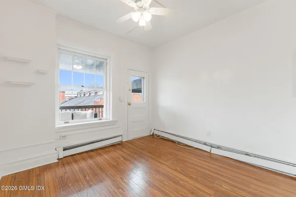 an empty room with wooden floor and windows