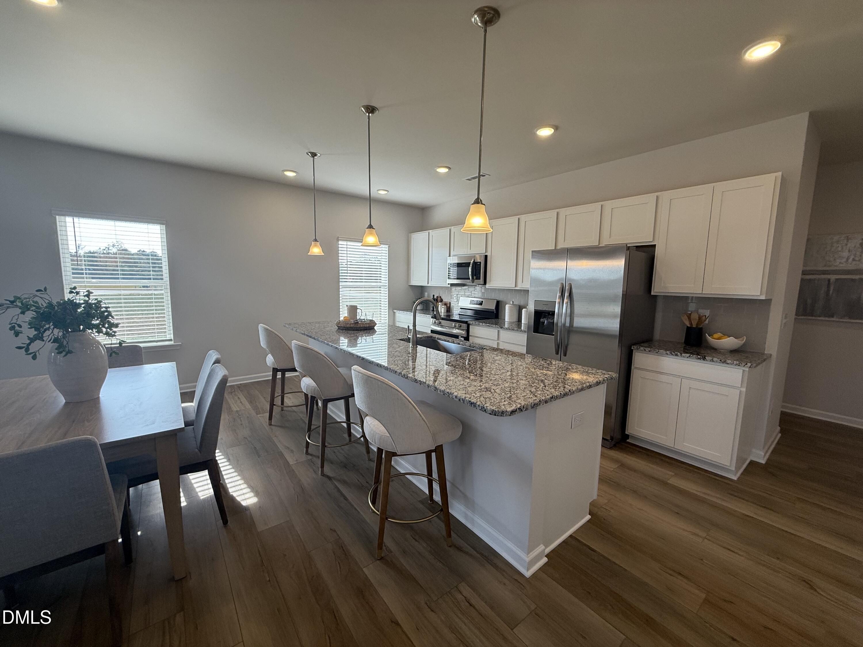 48 Spirit Spgs Road Smithfield, NC 27577 - Photo 8 of 24 a kitchen with stainless steel appliances granite countertop a stove a refrigerator a kitchen island a dining table and chairs