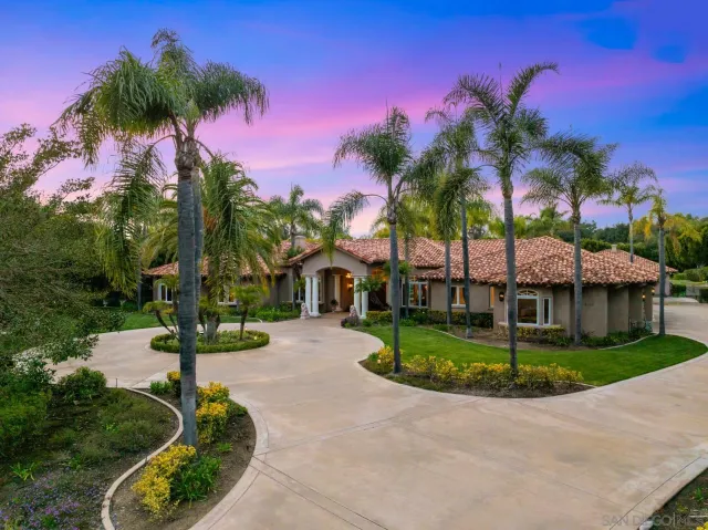 a front view of a house with a yard and potted plants