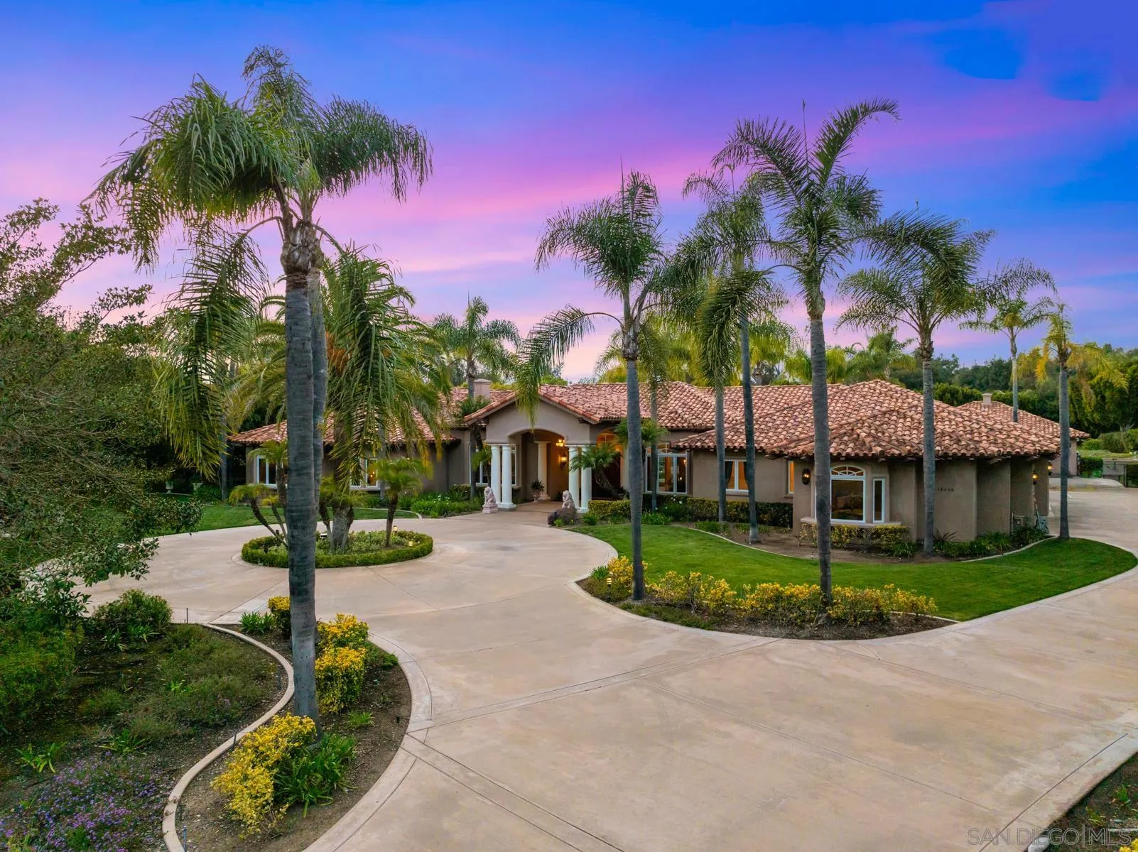 a front view of a house with a yard and potted plants
