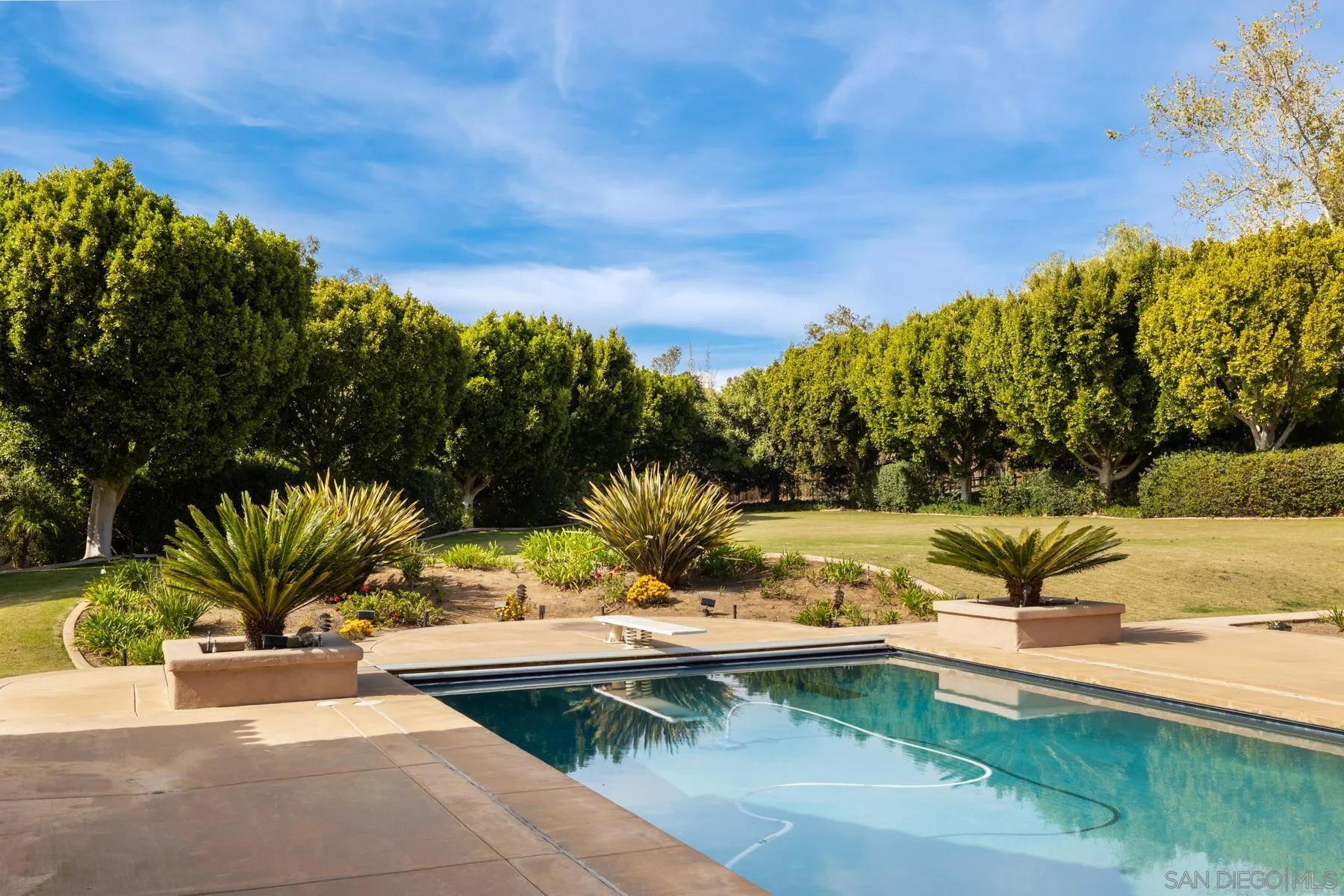 18050 Rancho La Cima Corte Rancho Santa Fe, CA 92067 - Photo 42 of 57 a view of a swimming pool with a lawn chairs under an umbrella