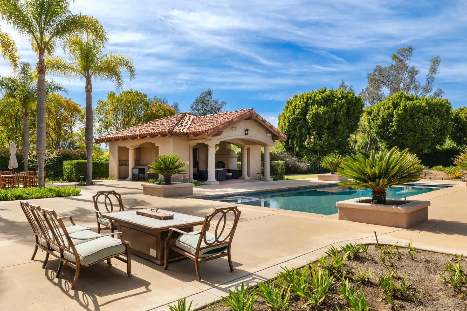 18050 Rancho La Cima Corte Rancho Santa Fe, CA 92067 - Photo 52 of 57 a view of a patio with table and chairs under an umbrella