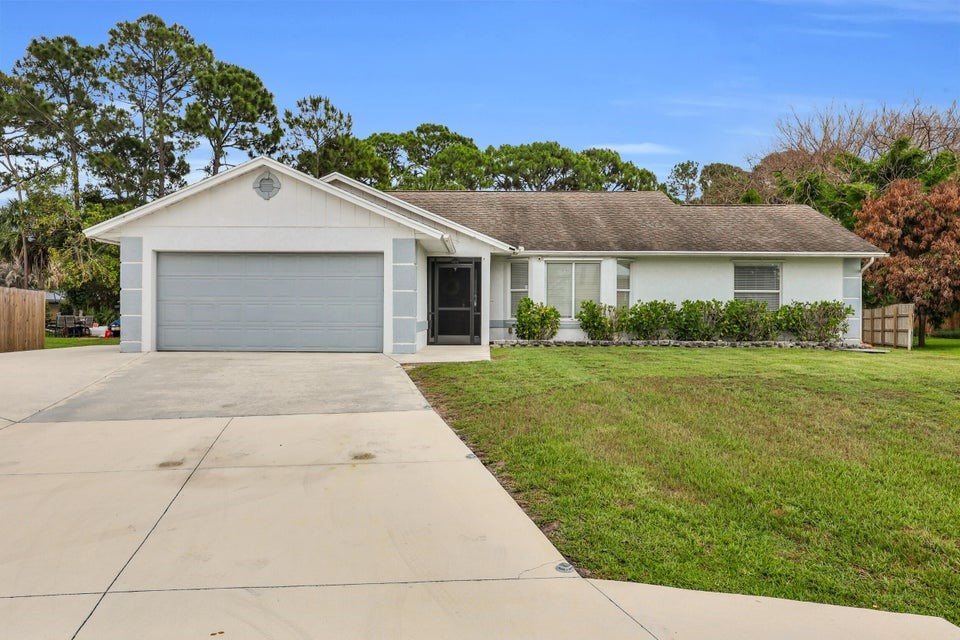 1950 Southwest Logwood Road Port St. Lucie, FL 34953 - Photo 1 of 32 a front view of a house with a yard and garage